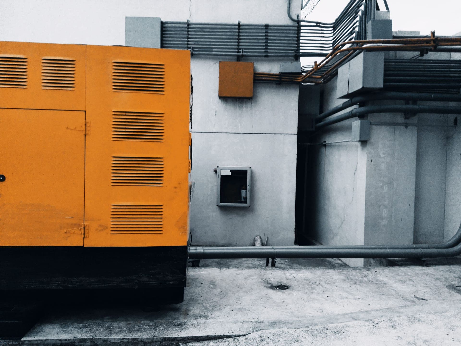 A portable generator running on a driveway outside a house during an overcast evening